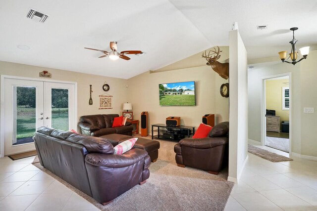 tiled living room with french doors, ceiling fan with notable chandelier, and vaulted ceiling