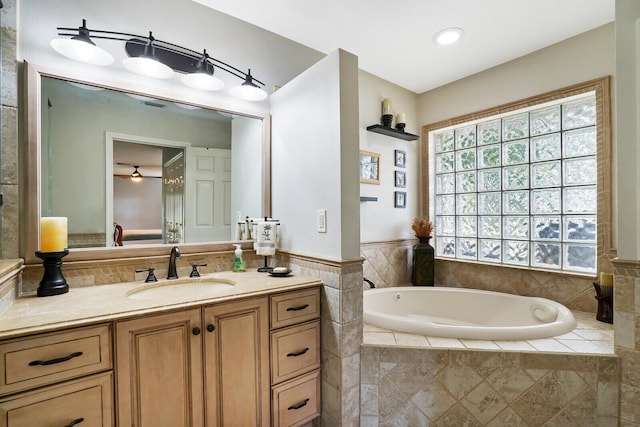 bathroom featuring tiled bath, vanity, and ceiling fan