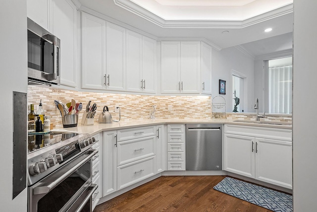 kitchen with tasteful backsplash, dark wood-type flooring, appliances with stainless steel finishes, white cabinets, and sink