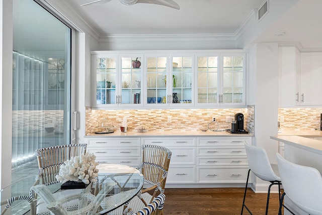 bar featuring white cabinetry, dark hardwood / wood-style floors, ceiling fan, tasteful backsplash, and ornamental molding