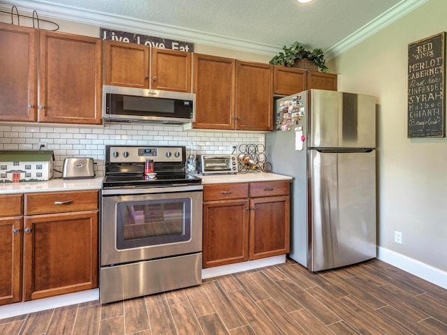 kitchen featuring crown molding, tasteful backsplash, appliances with stainless steel finishes, and dark wood-type flooring