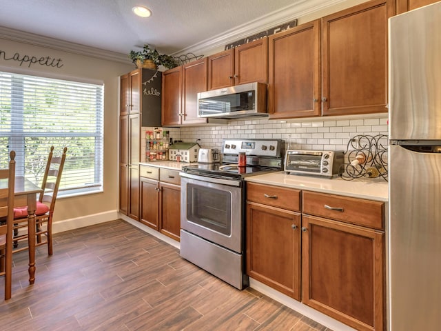 kitchen featuring backsplash, stainless steel appliances, and ornamental molding