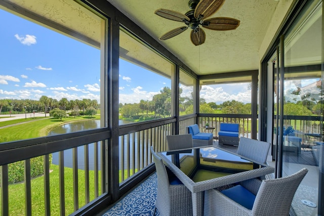 sunroom / solarium featuring ceiling fan and a water view