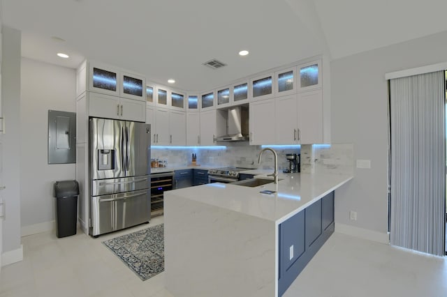 kitchen featuring kitchen peninsula, white cabinetry, backsplash, stainless steel appliances, and wall chimney exhaust hood