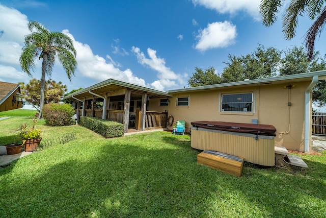 rear view of property featuring a hot tub and a yard