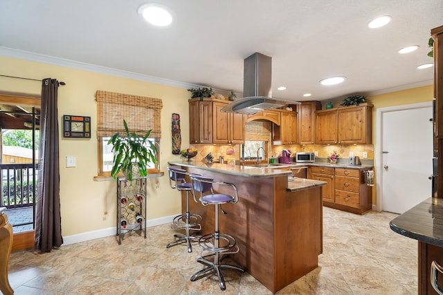 kitchen featuring kitchen peninsula, backsplash, island range hood, and light tile flooring