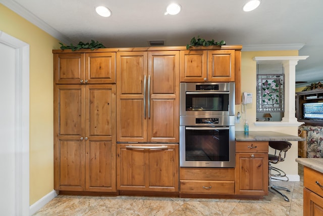 kitchen with light tile flooring, a kitchen bar, double oven, and ornamental molding