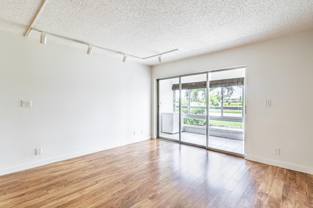 unfurnished room featuring rail lighting, a textured ceiling, and light wood-type flooring