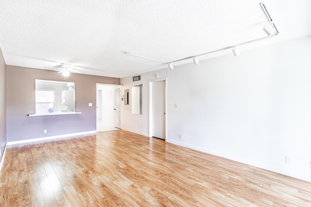 spare room with rail lighting, ceiling fan, light hardwood / wood-style flooring, and a textured ceiling