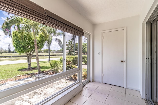 doorway with light tile floors, a textured ceiling, and a wealth of natural light