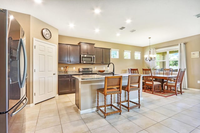 kitchen with an island with sink, a healthy amount of sunlight, appliances with stainless steel finishes, and a chandelier