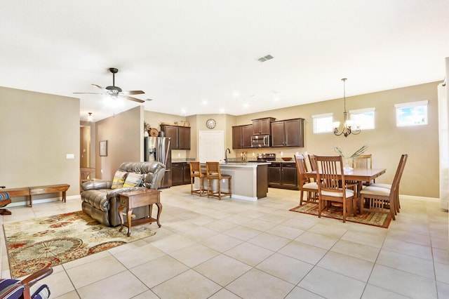 tiled living room with sink and ceiling fan with notable chandelier