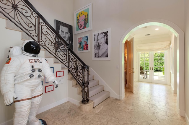 stairs with crown molding, french doors, light tile flooring, and a high ceiling