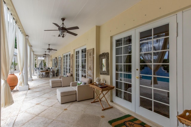 sunroom / solarium featuring decorative columns, ceiling fan, and french doors