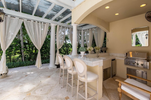 view of terrace featuring an outdoor wet bar, area for grilling, and an outdoor kitchen