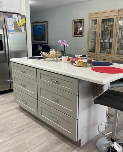 interior space featuring gray cabinetry, light wood-type flooring, and stainless steel refrigerator with ice dispenser