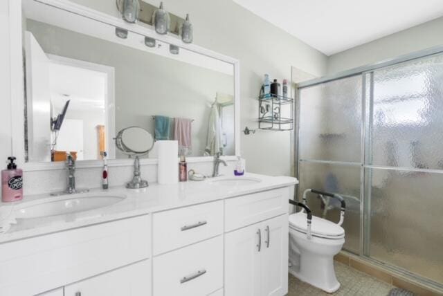 bathroom featuring toilet, vanity with extensive cabinet space, walk in shower, tile flooring, and dual sinks