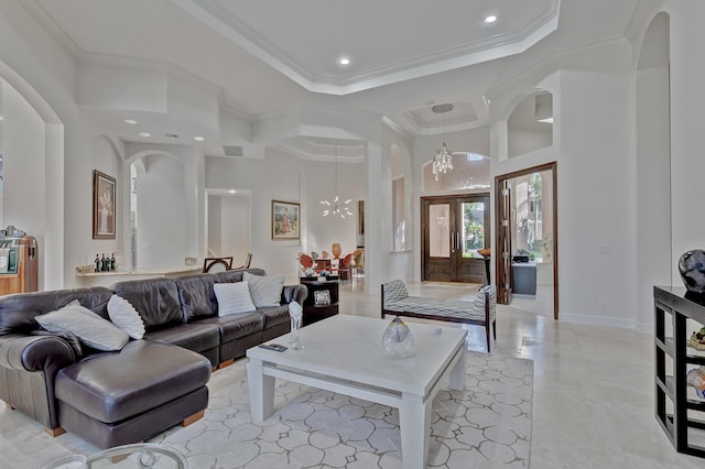 living room with ornamental molding, french doors, an inviting chandelier, and a tray ceiling