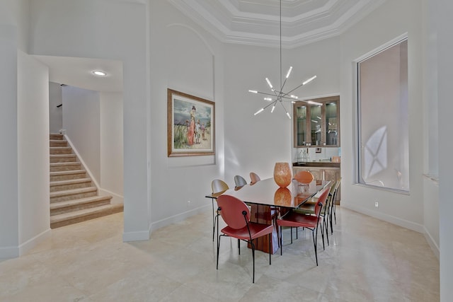 dining area featuring a raised ceiling, light tile floors, a towering ceiling, a chandelier, and ornamental molding