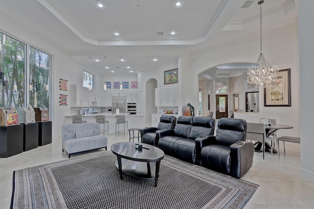 living room with an inviting chandelier, a raised ceiling, ornamental molding, and light tile floors