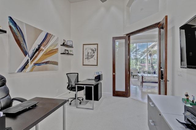 office with french doors, light colored carpet, and a high ceiling