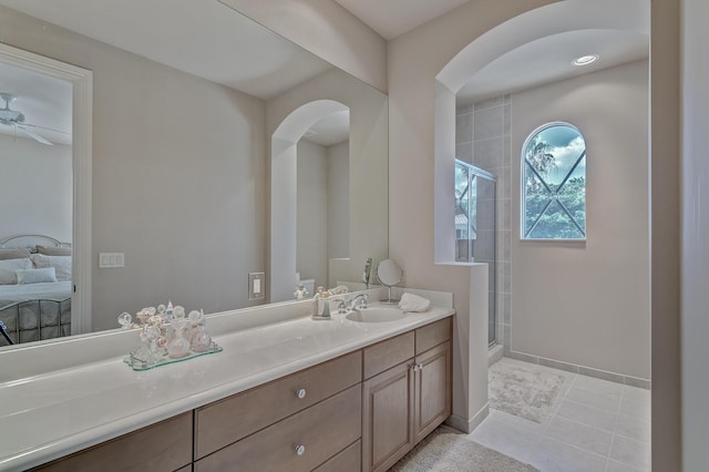 bathroom with a shower with door, ceiling fan, tile flooring, and vanity