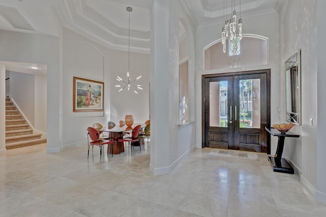 tiled foyer entrance featuring a notable chandelier, a raised ceiling, a high ceiling, and french doors