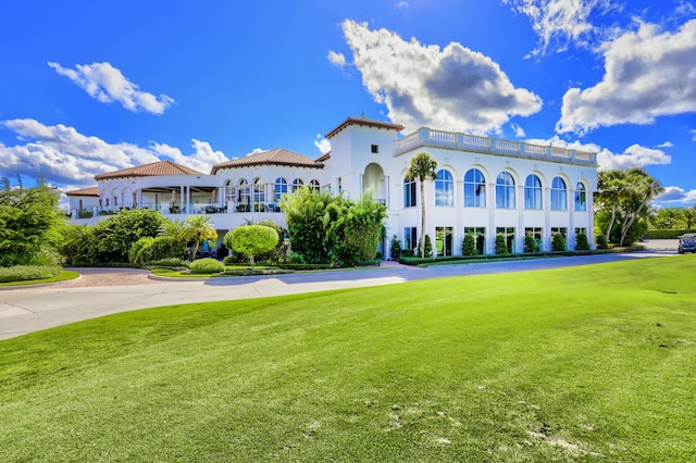 back of property featuring a balcony and a yard