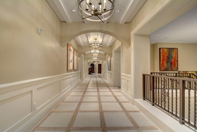 hall with light tile floors, a notable chandelier, and beam ceiling