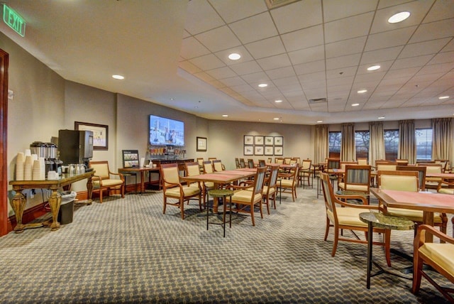 carpeted dining space with a paneled ceiling