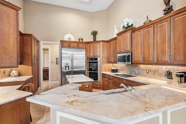 kitchen featuring a high ceiling, light stone countertops, appliances with stainless steel finishes, sink, and tasteful backsplash