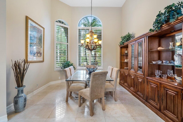 dining area featuring a high ceiling, plenty of natural light, a chandelier, and light tile flooring