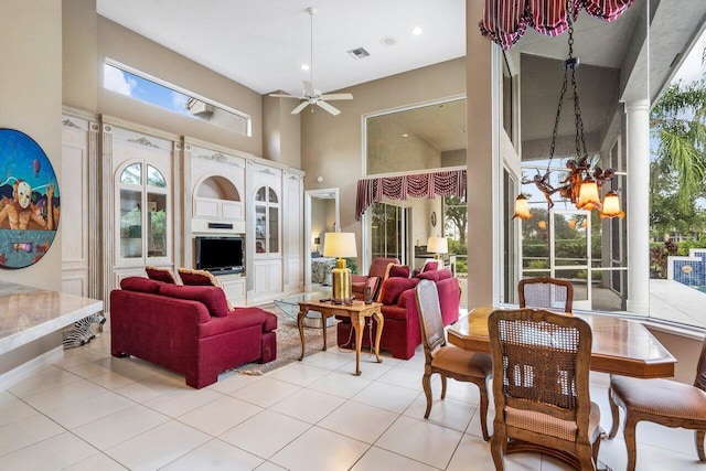 interior space with ceiling fan with notable chandelier, a towering ceiling, and light tile flooring