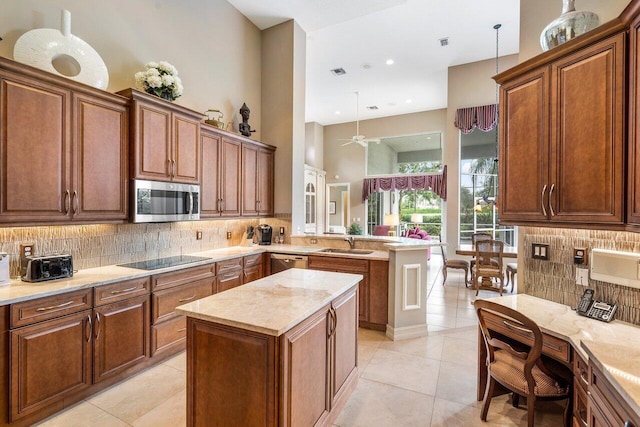 kitchen with light tile floors, a kitchen island, ceiling fan, appliances with stainless steel finishes, and backsplash