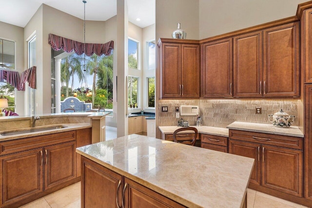 kitchen with light tile floors, hanging light fixtures, a center island, and sink