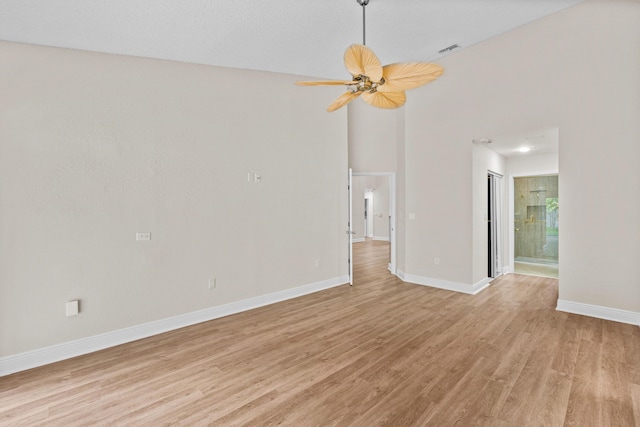 unfurnished room featuring a high ceiling, ceiling fan, and light hardwood / wood-style flooring