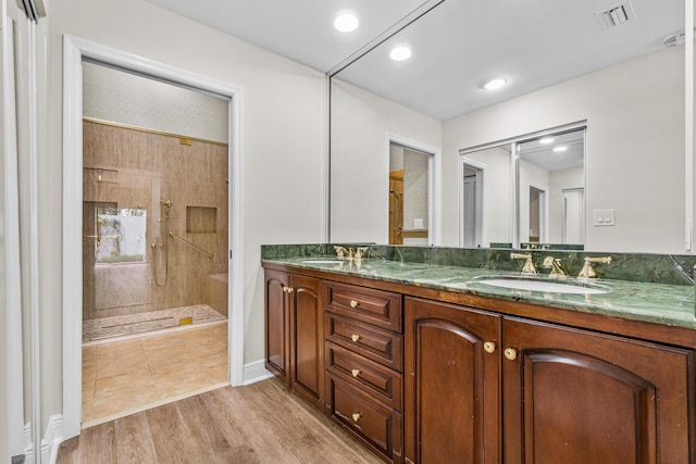 bathroom with a tile shower, tile flooring, and dual bowl vanity