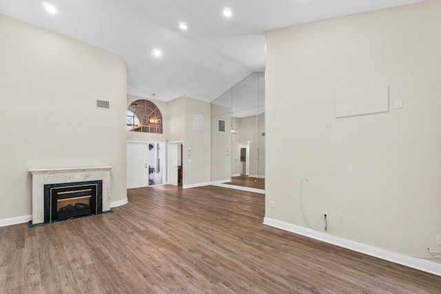 unfurnished living room featuring a high end fireplace, high vaulted ceiling, and dark hardwood / wood-style floors