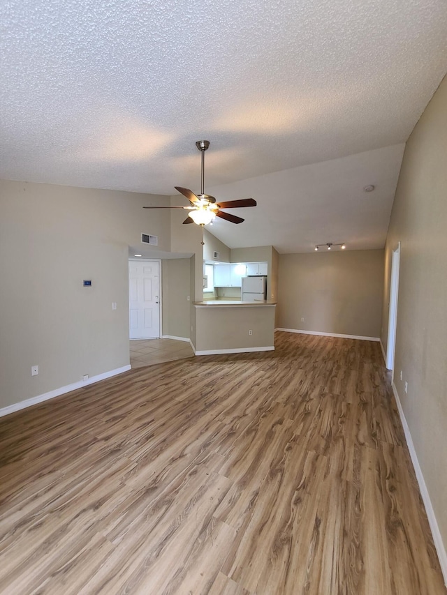 empty room with ceiling fan, a textured ceiling, wood-type flooring, and vaulted ceiling