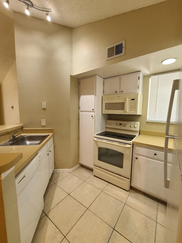 kitchen with light tile floors, white appliances, sink, white cabinets, and track lighting