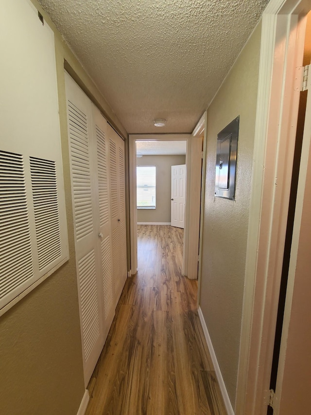 hall with a textured ceiling and dark hardwood / wood-style floors