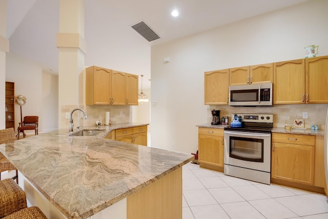 kitchen featuring kitchen peninsula, light stone countertops, a breakfast bar, high vaulted ceiling, and stainless steel appliances