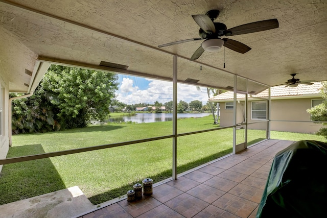 unfurnished sunroom with ceiling fan and a water view