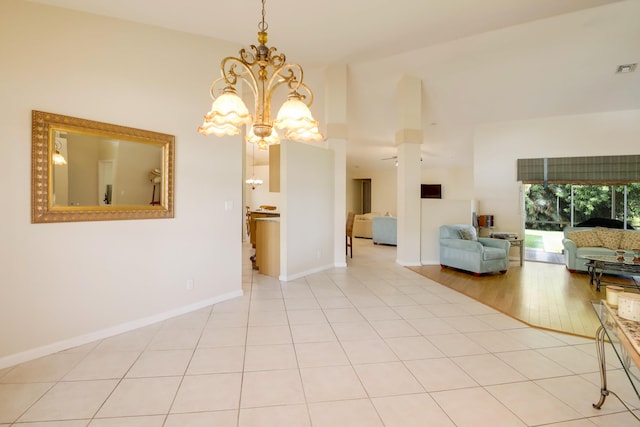 unfurnished dining area with ceiling fan with notable chandelier and light tile flooring