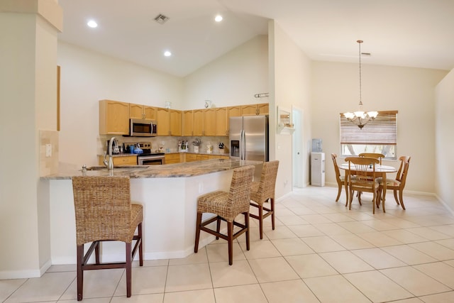 kitchen with a chandelier, a breakfast bar, high vaulted ceiling, and appliances with stainless steel finishes