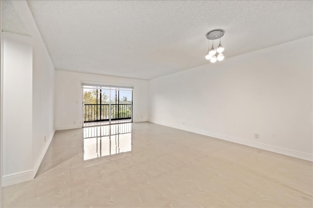 empty room featuring a chandelier, light tile floors, and a textured ceiling