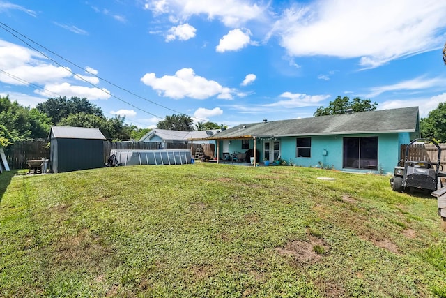 rear view of property featuring a yard and a storage unit