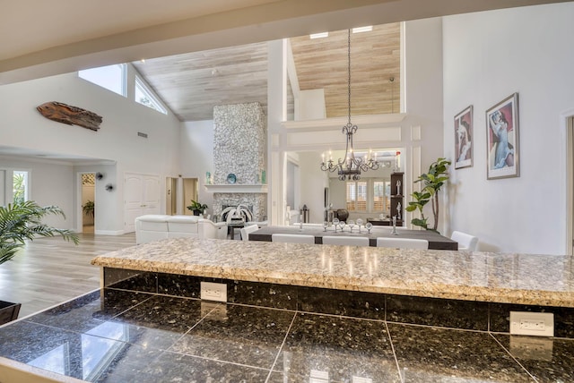 kitchen with a large fireplace, hanging light fixtures, a high ceiling, and an inviting chandelier