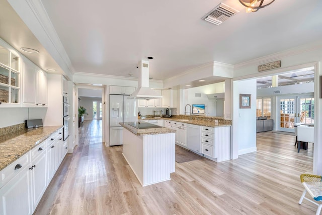 kitchen with white cabinetry, a center island, light stone countertops, white appliances, and custom exhaust hood