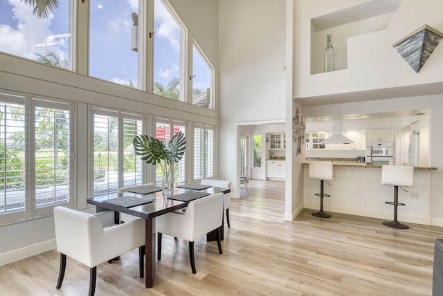 dining area with light hardwood / wood-style flooring and a towering ceiling